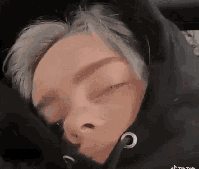a close up of a person sleeping with their eyes closed and a hoodie on .