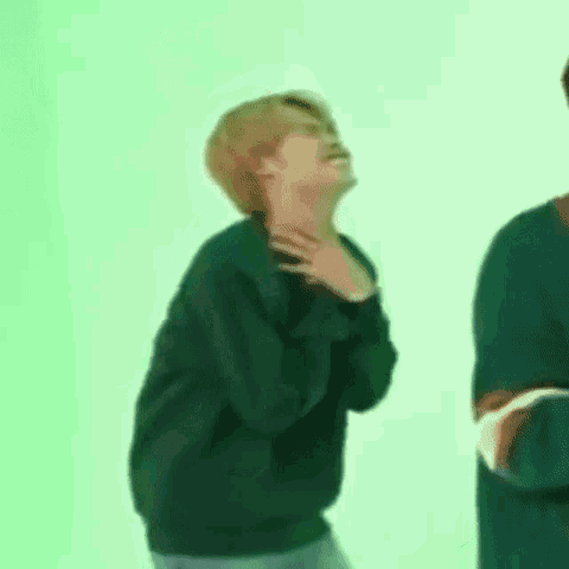 a man in a green sweater is standing next to another man in a green shirt .