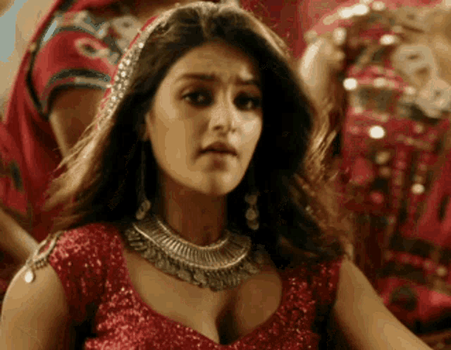 a close up of a woman wearing a red top and silver necklace