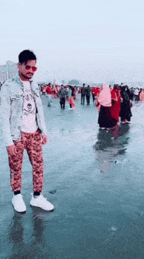 a man wearing sunglasses is standing on a beach with people