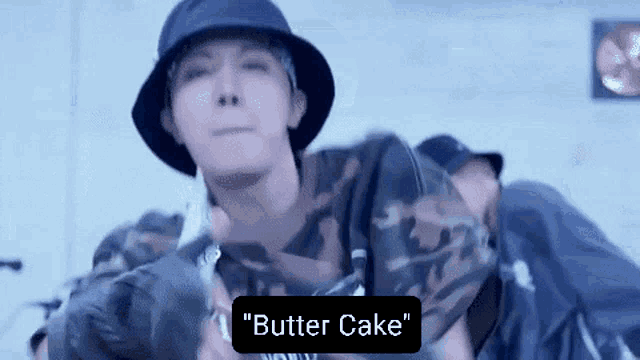 a man wearing a bucket hat is holding a knife and says " butter cake " on the bottom