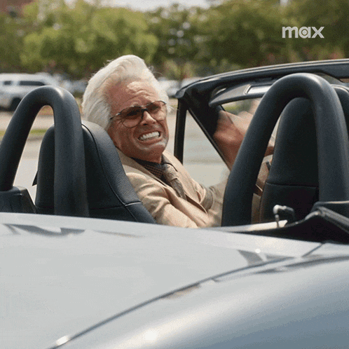 a man is sitting in a car with the word max on the bottom right