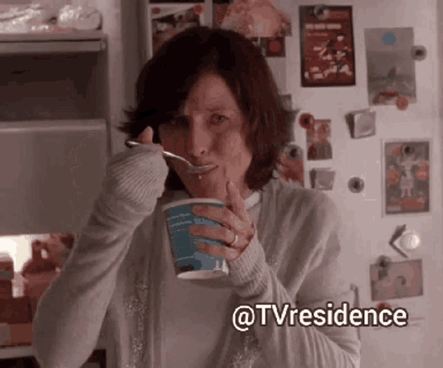 a woman is eating a cup of yogurt with a spoon in her mouth and the words @tvresidence are below her