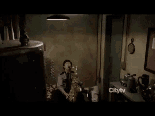 a man is playing a saxophone in a room with a citytv logo on the corner