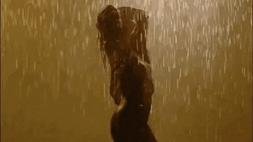 a woman is standing in the rain holding a baby in her arms .