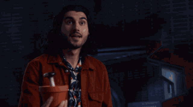a man in a red shirt is holding a potted plant in his hands