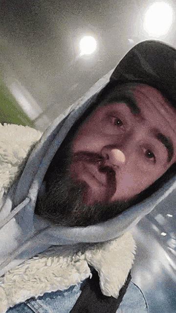 a man with a beard is wearing a hooded jacket and a hat