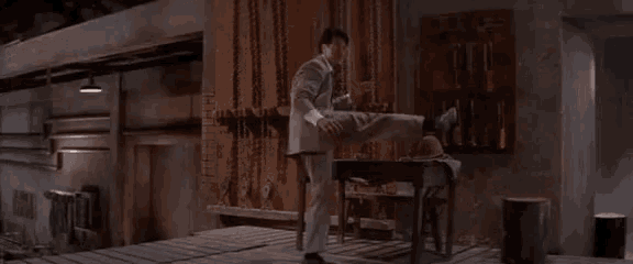 a man in a suit and tie is kicking another man 's leg .