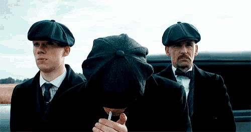 three men in suits and hats are standing next to each other .