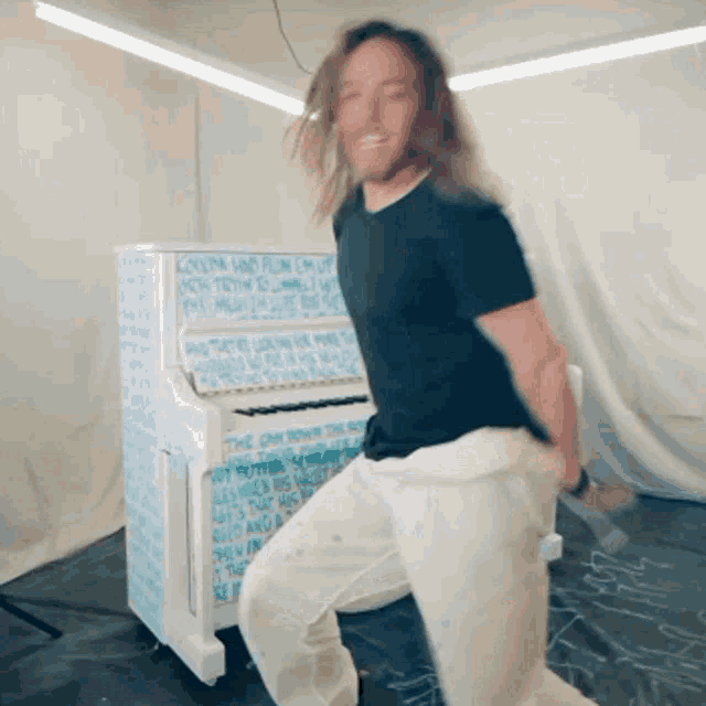 a man in a black shirt is dancing in front of a piano that says " the car down the road " on it