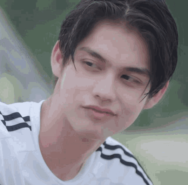 a close up of a young man 's face wearing a white shirt with black stripes on the side .