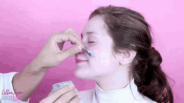 a woman is getting her face painted by a person .