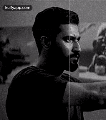 a black and white photo of a man with a beard looking at the camera .