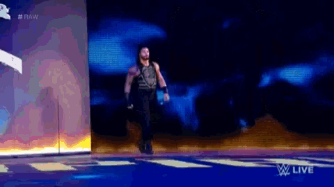 roman reigns is walking on a stage during a wrestling match