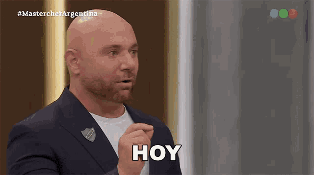 a bald man in a suit is making a funny face and saying hoy