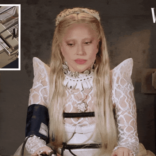 a woman in a white dress has a blood pressure cuff around her wrist