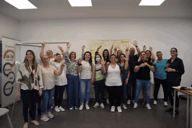 a group of people are posing for a photo in front of a board that says " o novo " on it