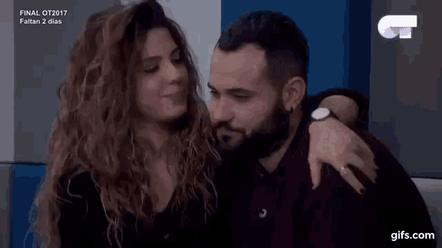 a woman is kissing a man on the cheek while sitting next to him .