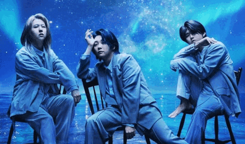 three men in suits are sitting in chairs in front of a blue sky .