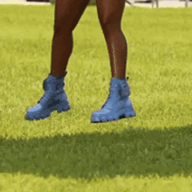 a person wearing blue boots is standing on a grassy field .