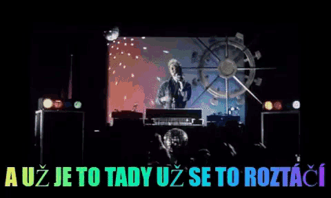 a man playing a keyboard in front of a screen that says a uz je to tady uz se to roztaci