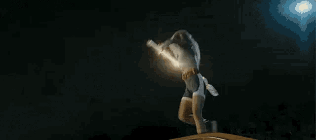 a woman is holding a sword in her hand in a dark room .