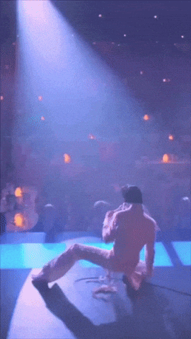 a man in a pink suit is kneeling on a stage in front of a crowd