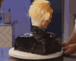 a cake that looks like a man 's head is being eaten by someone