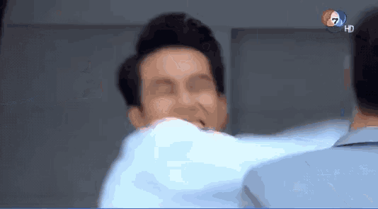 a man in a suit is being punched in the face by another man in a blue suit .