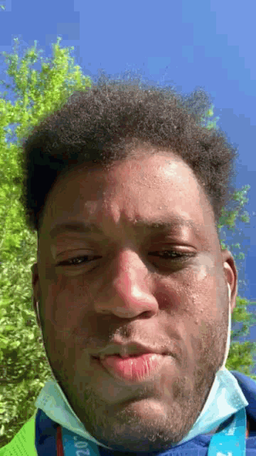 a man wearing a mask and ear buds is making a face .