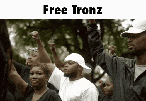 a group of people are holding their fists up in the air and the words free tronz are above them .
