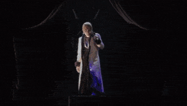 a man is singing into a microphone while holding a sword .