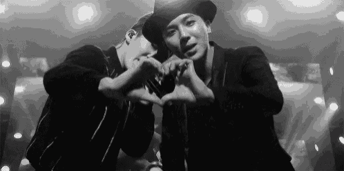 a couple of men are making a heart shape with their hands .