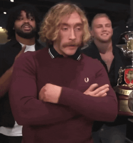 a man wearing a maroon sweater with a crest on it