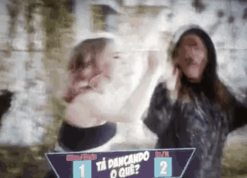 two women are dancing in front of a sign that says ' ta dancando o que ? '