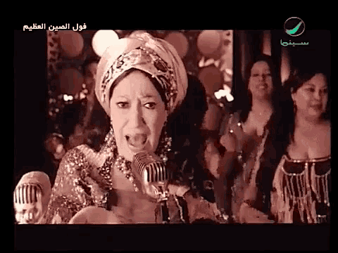 a woman is singing into a microphone with arabic writing on the screen
