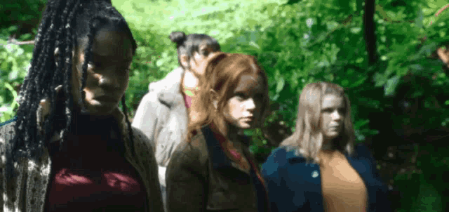 a group of young women are standing in a row in the woods