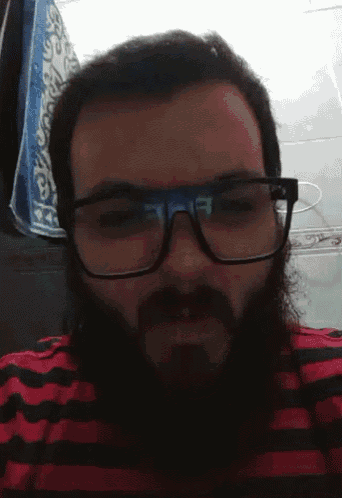 a man with glasses and a beard wears a red and black striped shirt