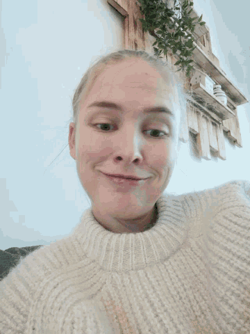 a young girl wearing a white sweater is smiling