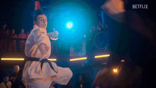 a man in a karate uniform is doing a kick in front of a netflix sign