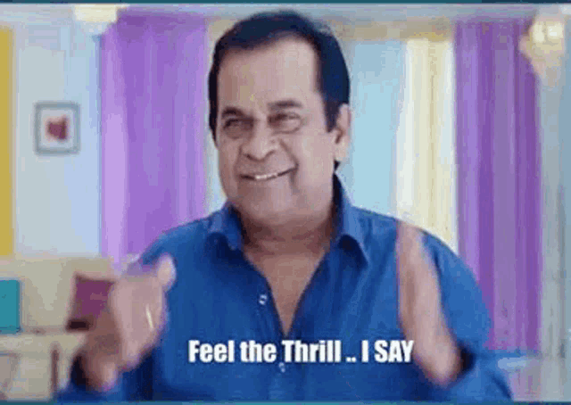 a man in a blue shirt is smiling and saying `` feel the thrill , i say '' .