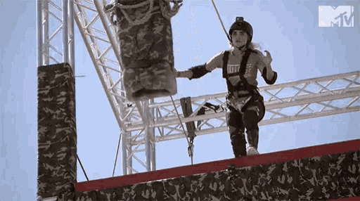 a woman wearing a helmet and a t-shirt that says ' army ' on it is standing on a wall