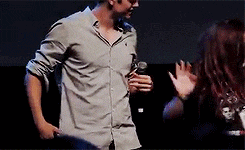 a man in a grey shirt is standing next to a woman in a black shirt holding a microphone .