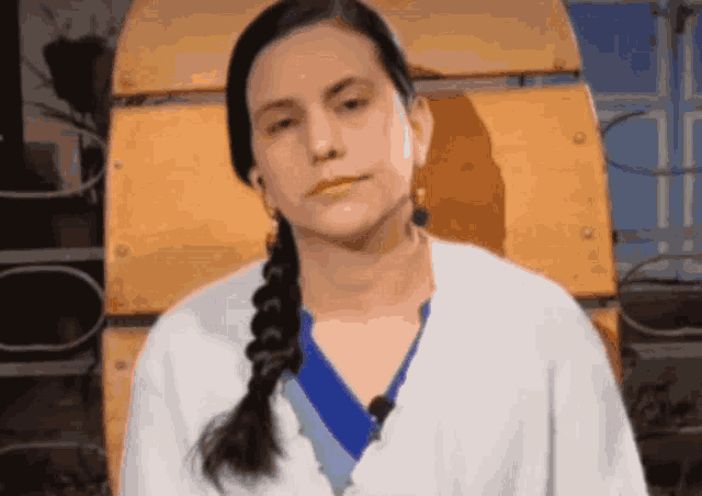 a woman with braided hair is wearing a white sweater and earrings