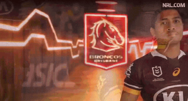 a man stands in front of a sign that says broncos brisbane on it