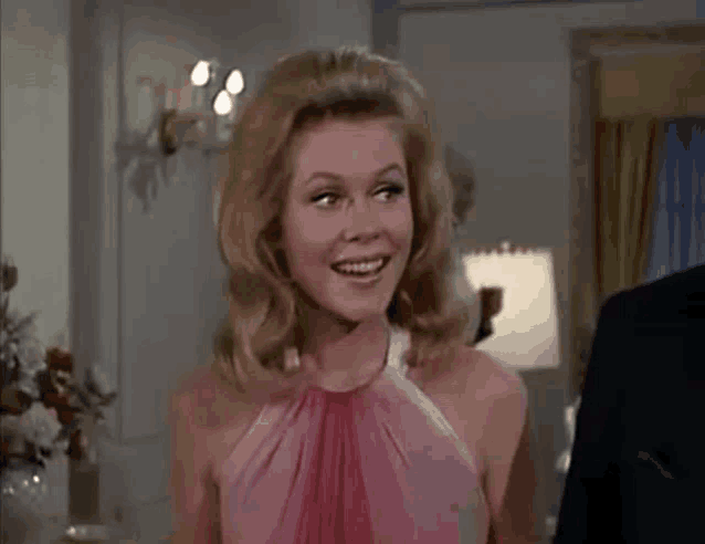 a woman in a pink dress is smiling in a room .
