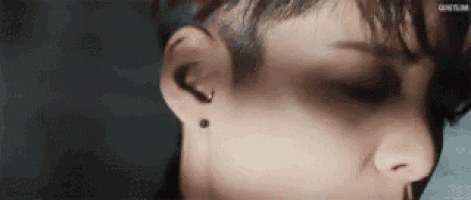 a close up of a person 's face with a piercing in their ear and nose .