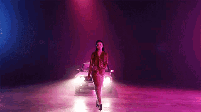 a woman is standing in front of a car with purple lights on it