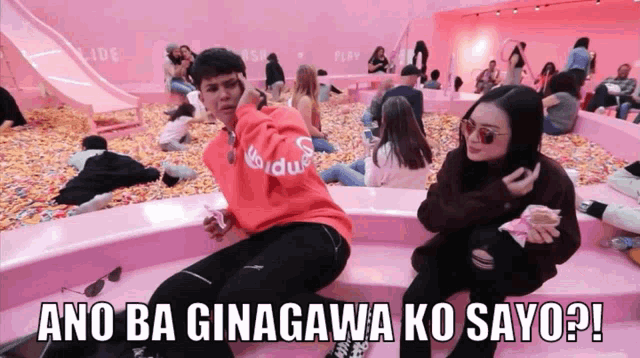 a man and a woman are sitting in a pink room with the words ano ba ginagawa ko sayo written on the bottom
