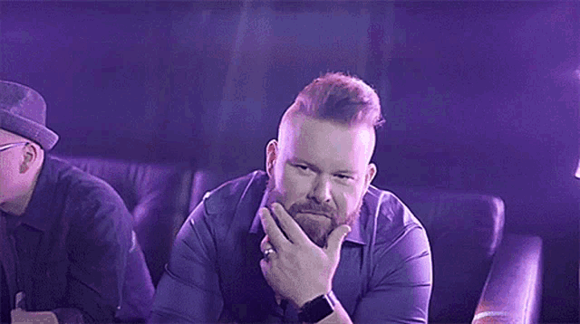 a man with a beard holds his hand to his chin